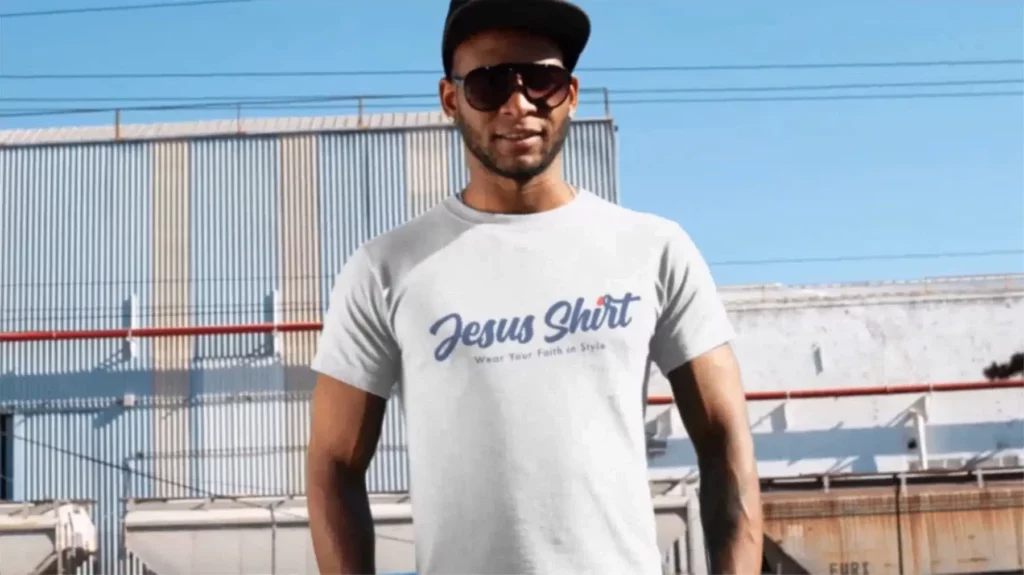 A man proudly wears a white Jesus T-shirt, emblazoned with the iconic Jesus Shirt logo, symbolizing faith and unity.